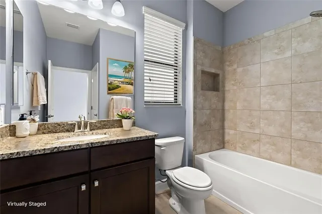 a bathroom with a granite countertop bathtub sink vanity mirror and toilet