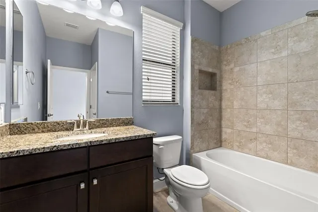a bathroom with a granite countertop sink toilet mirror vanity and bathtub