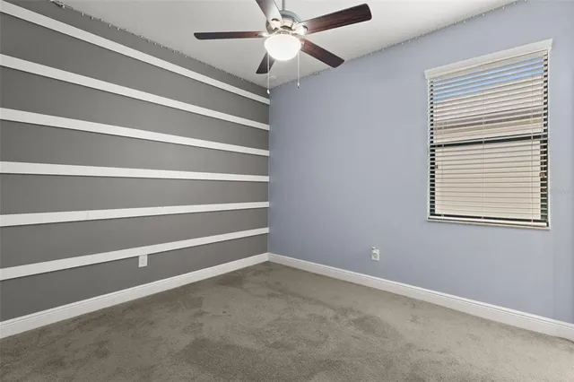 a view of an empty room with a window and a ceiling fan