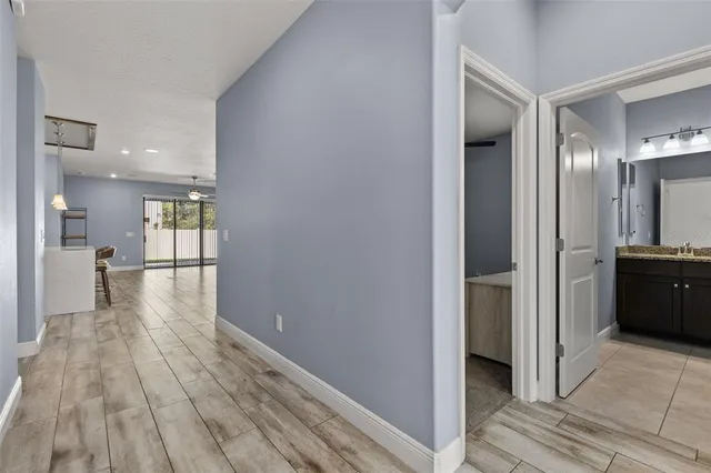 a view of a hallway with wooden floor a bathroom and a sink