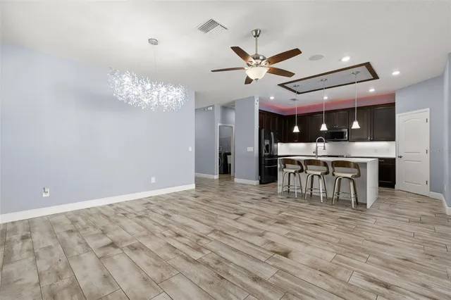 a view of a room with wooden floor a ceiling fan a fireplace and windows
