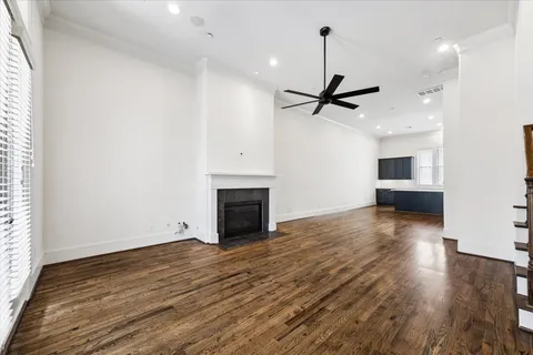 a view of a livingroom with a fireplace a ceiling fan and wooden floor