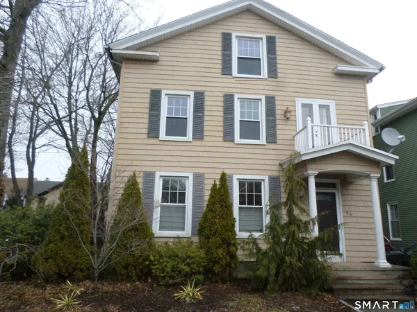 a front view of a house with plants and trees