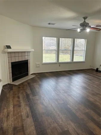 an empty room with wooden floor fireplace and windows