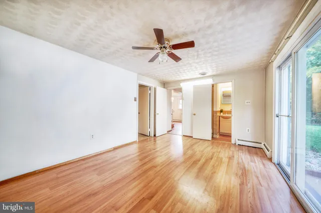 a view of empty room with wooden floor and fan