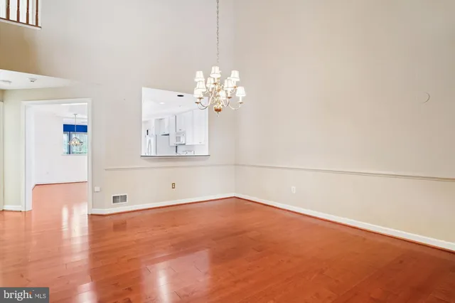 a view of a kitchen with an empty room and wooden floor