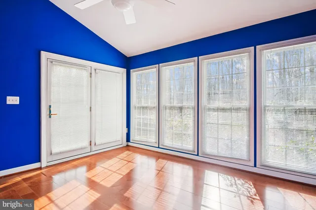 a view of an empty room with wooden floor and a chandelier