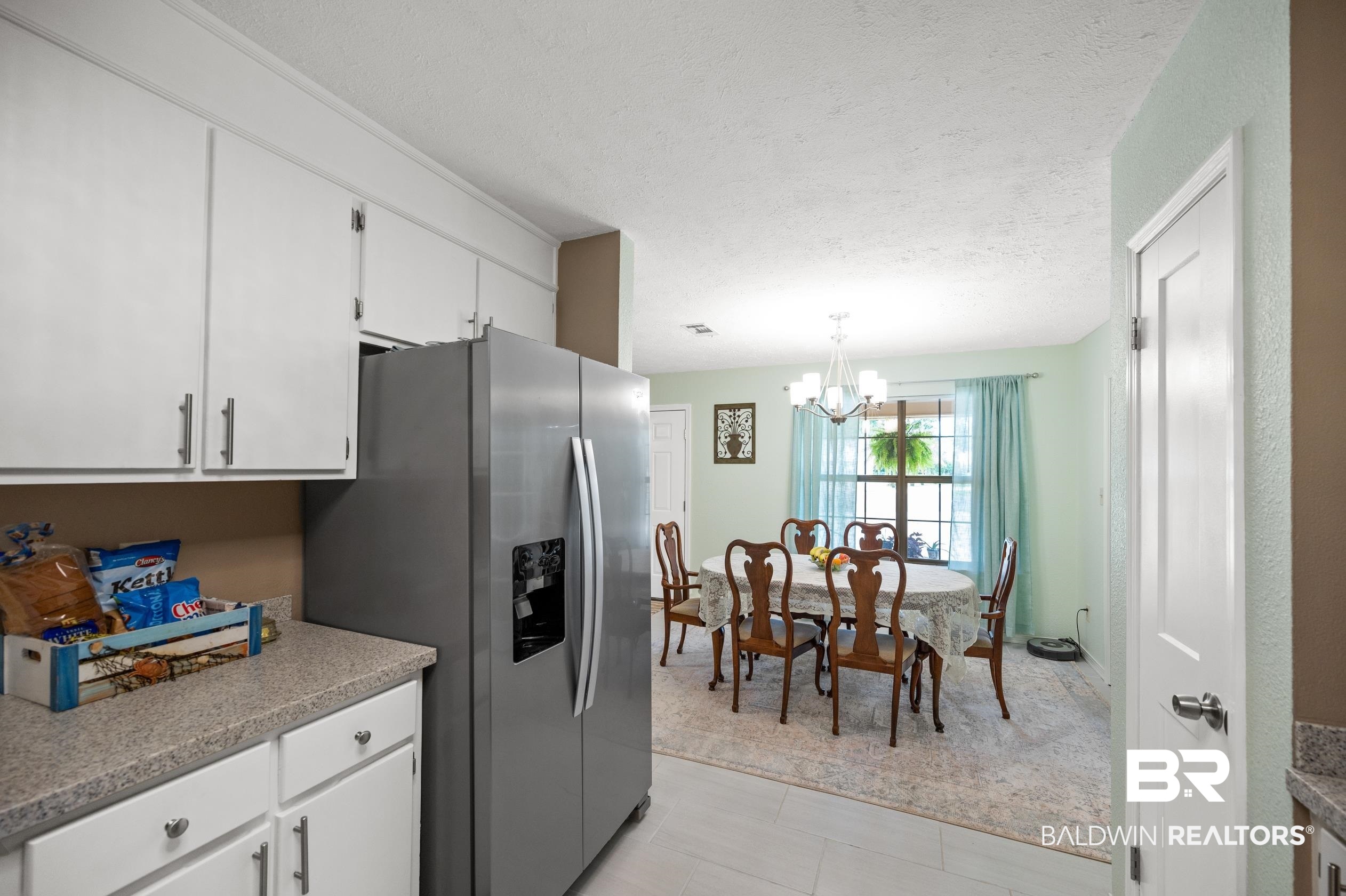 2772 Santa Rosa Circle Lillian, AL 36549 - Photo 14 of 50 Kitchen with white cabinetry, light tile patterned floors, an inviting chandelier, decorative light fixtures, and stainless steel refrigerator with ice dispenser