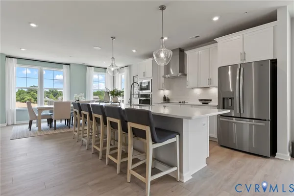 a kitchen with stainless steel appliances kitchen island granite countertop a dining table chairs refrigerator and sink