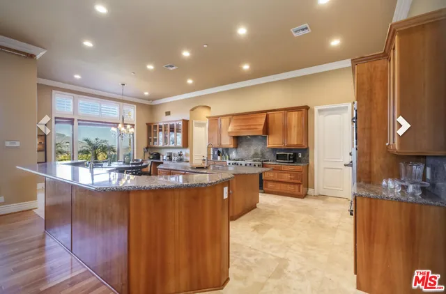 a view of a kitchen with kitchen island a large counter top stainless steel appliances and cabinets
