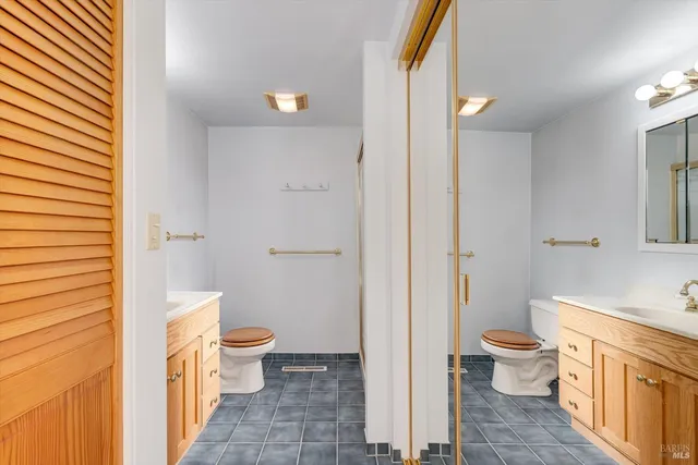 a bathroom with a granite countertop toilet a sink and a mirror