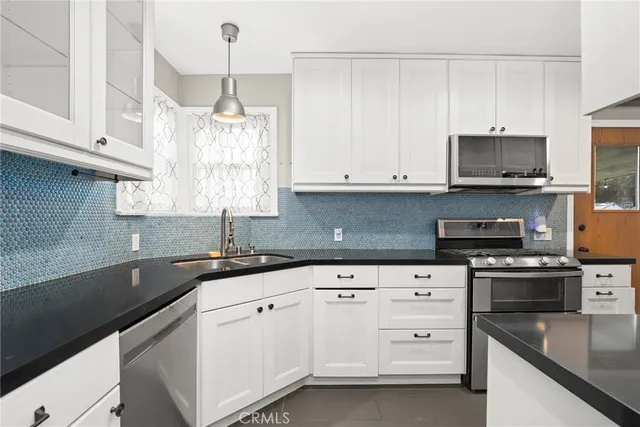 a kitchen with white cabinets white stainless steel appliances and sink