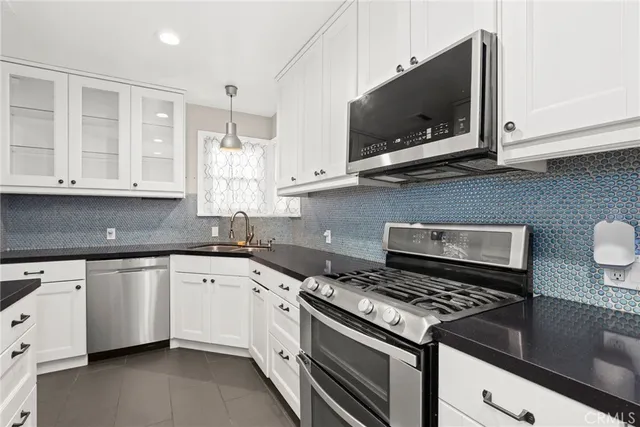 a kitchen with granite countertop a stove top oven microwave and cabinets