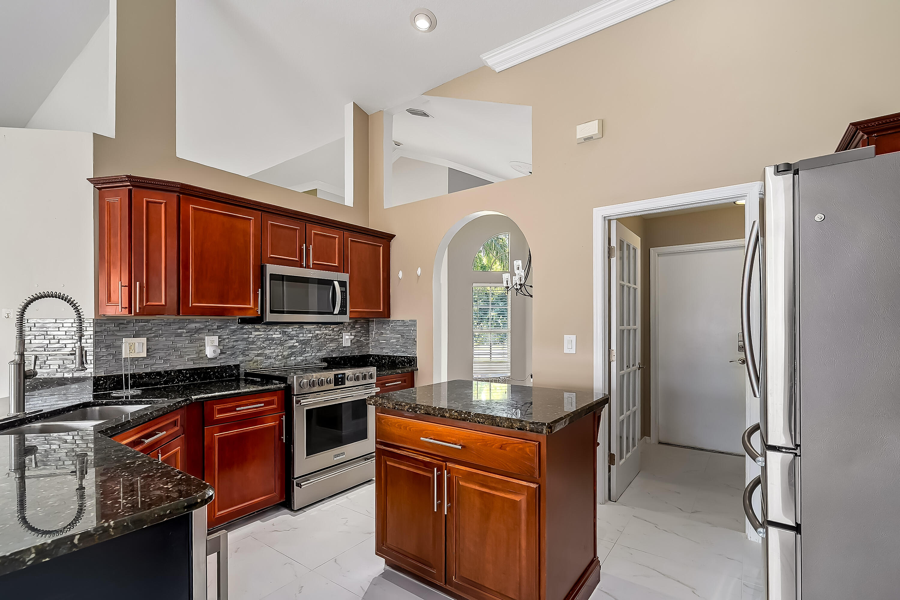 2962 Southwest Coastal Terrace Port St. Lucie, FL 34953 - Photo 28 of 59 a kitchen with stainless steel appliances granite countertop a stove a sink and a refrigerator