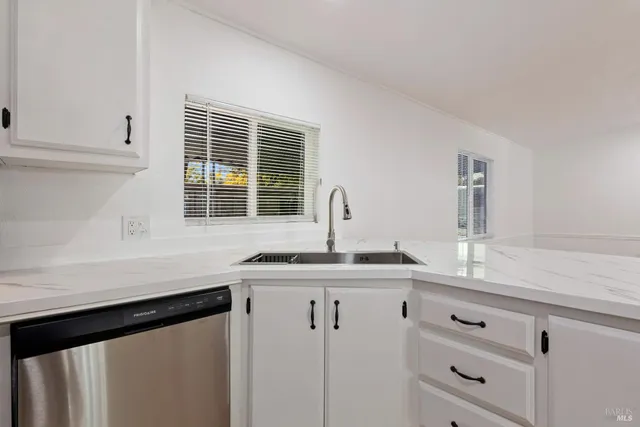 a kitchen with granite countertop white cabinets and a sink