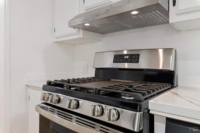a stove sitting inside of a kitchen with white cabinets