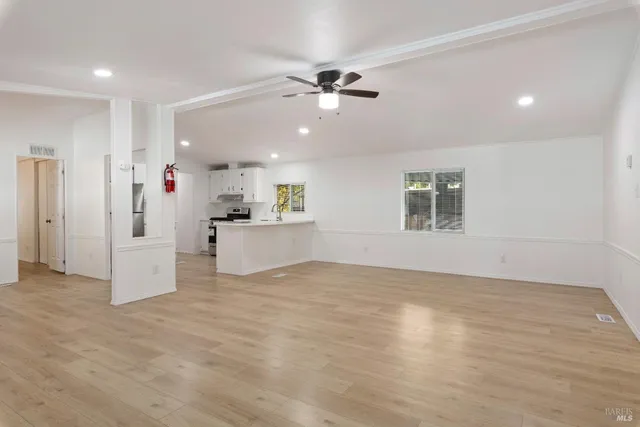 a view of an empty room with a window and kitchen view