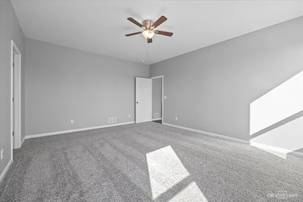 an empty room with ceiling fan and window