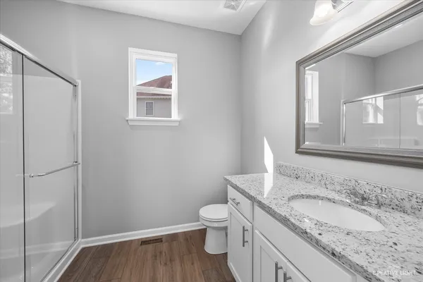 a bathroom with a granite countertop sink toilet and mirror