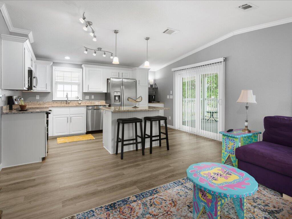 340 Pear Tree Avenue Goodland, FL 34140 - Photo 9 of 24 a open kitchen with stainless steel appliances granite countertop a stove a refrigerator a kitchen island a dining table and chairs with wooden floor