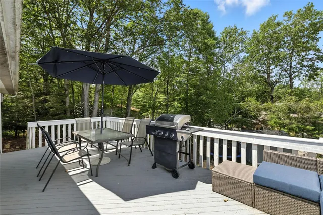 a view of a roof deck with table and chairs under an umbrella with wooden floor