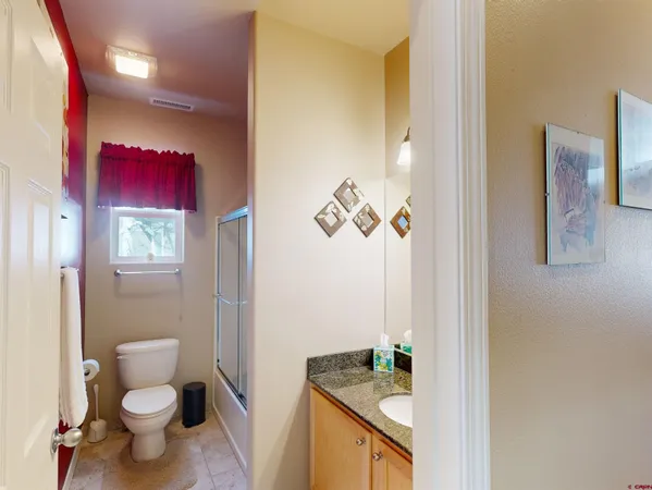 a bathroom with a granite countertop sink mirror vanity and toilet