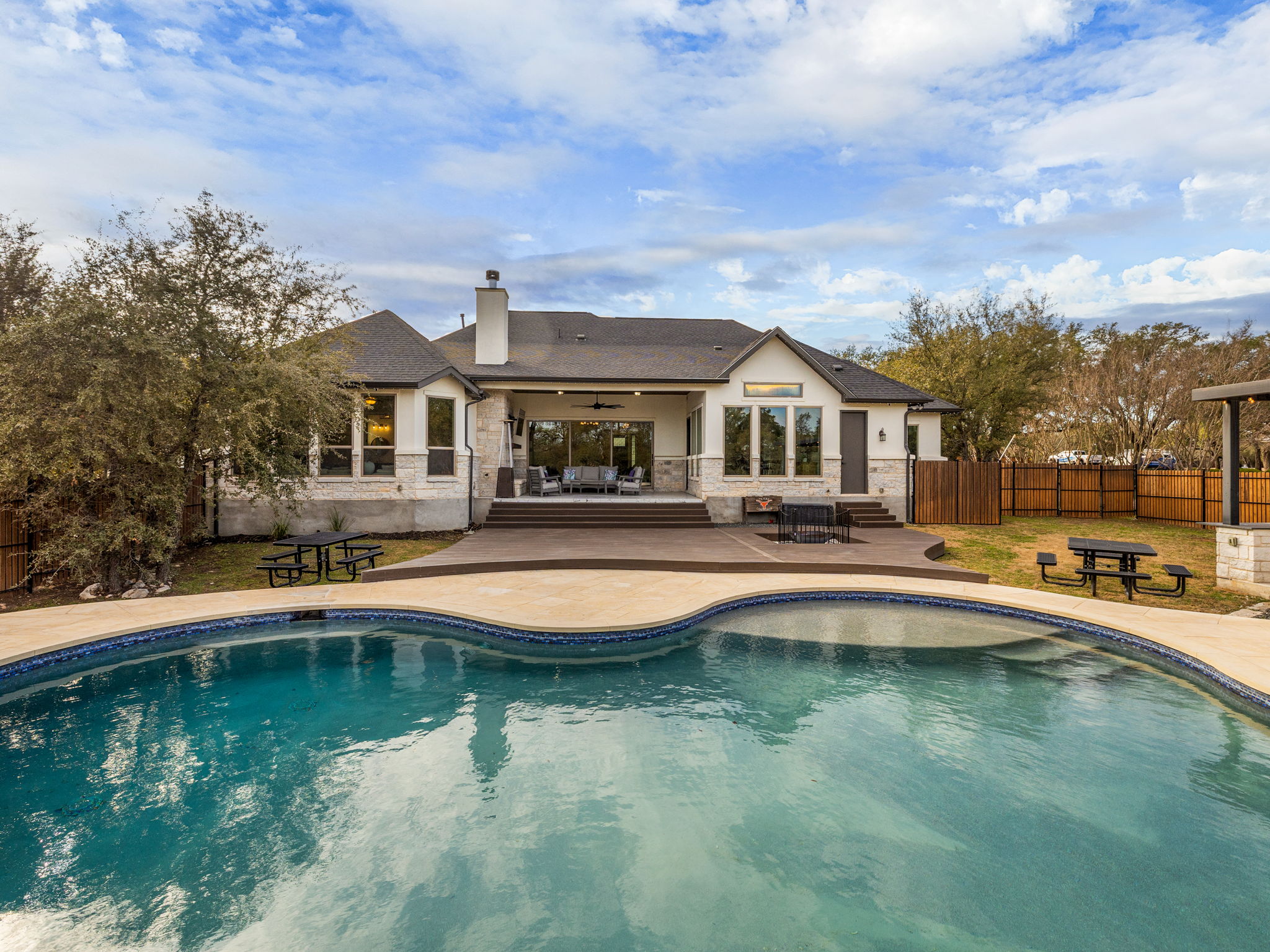 901 Clark Cove Road Buda, TX 78610 - Photo 29 of 37 Rear view of house with a ceiling fan, a fenced backyard, a patio, a chimney, and stone siding