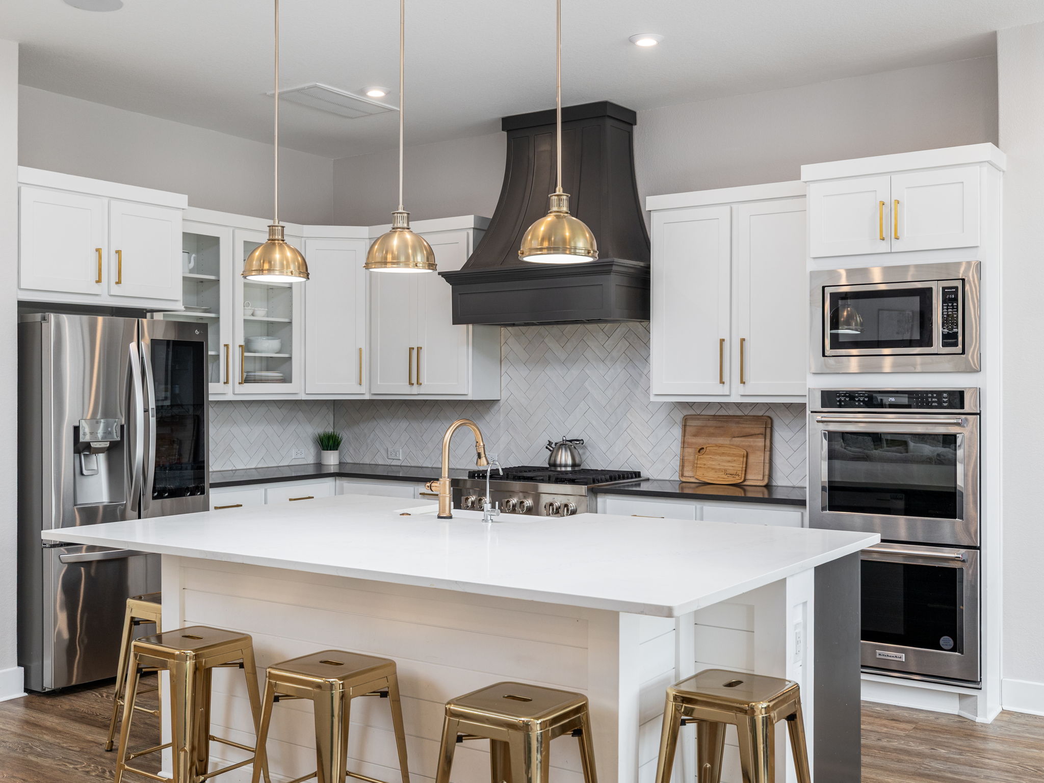 901 Clark Cove Road Buda, TX 78610 - Photo 3 of 37 Kitchen with dark wood-type flooring, stainless steel appliances, decorative light fixtures, a breakfast bar, and two tone color scheme
