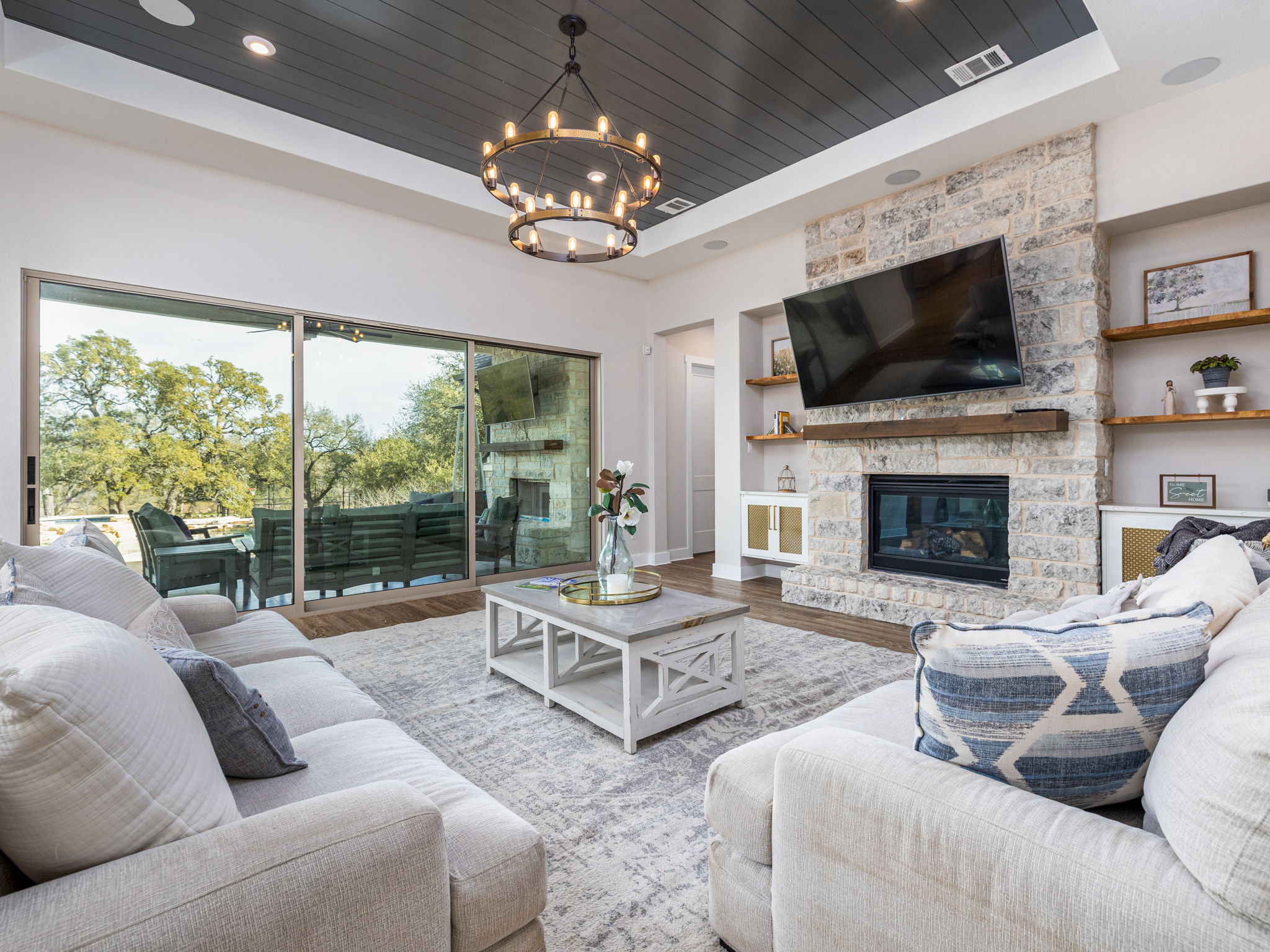 901 Clark Cove Road Buda, TX 78610 - Photo 6 of 37 Living area with a stone fireplace, wood finished floors, a wood tray ceiling, and hanging lights