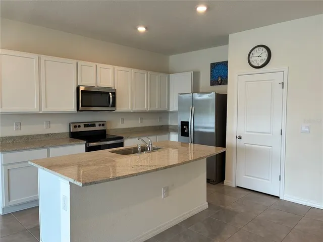 a kitchen with a refrigerator a stove top oven a clock and cabinets