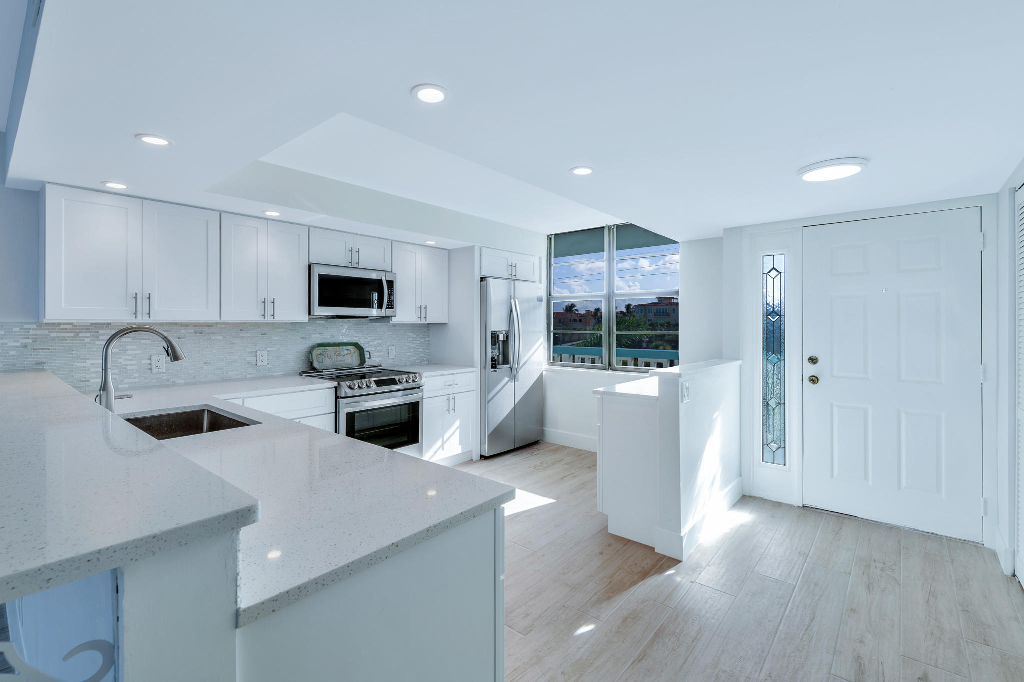 900 Ocean Drive, Unit 403 Juno Beach, FL 33408 - Photo 5 of 15 a kitchen with white cabinets and stainless steel appliances