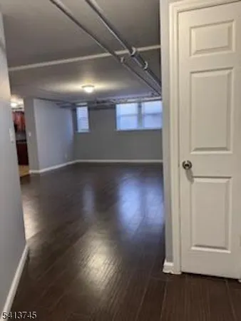 an empty room with wooden floor cabinet and windows
