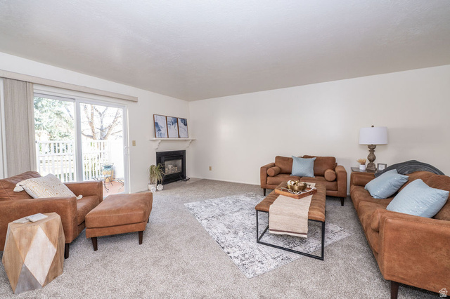 Living area featuring a fireplace with flush hearth and carpet