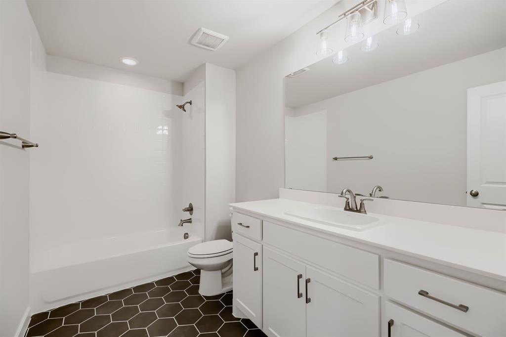 4407 Windy Point Road Oak Point, TX 75068 - Photo 22 of 27 Bathroom featuring hexagonal floor tiles, a white vanity with brushed nickel hardware, a single basin sink, and an integrated tub and shower with white subway tile surround