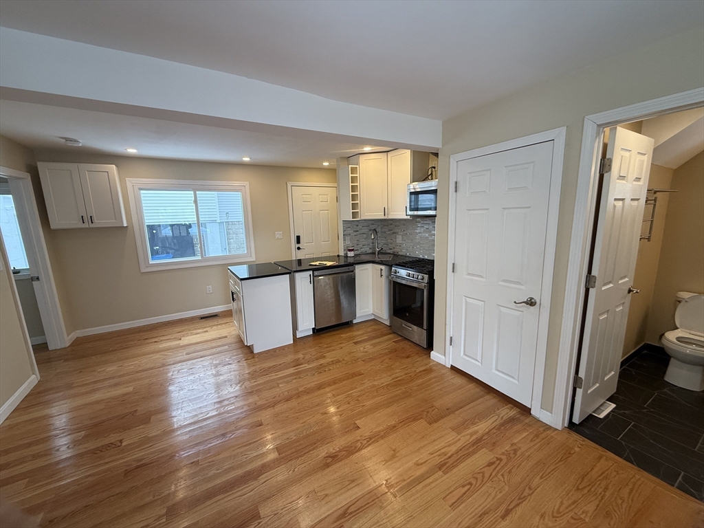7 Williston Road, Unit A Belmont, MA 02478 - Photo 6 of 10 an empty room with wooden floor and windows