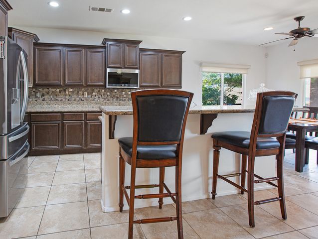 a kitchen with granite countertop a table chairs microwave and refrigerator