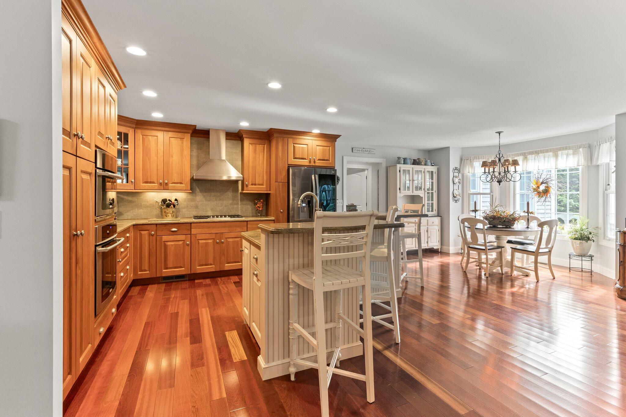 9 Briar Spring Road Orleans, MA 02653 - Photo 16 of 65 a kitchen with stainless steel appliances kitchen island granite countertop a stove a refrigerator a dining table and chairs with wooden floor