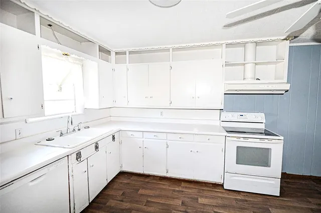 a kitchen with white cabinets and wooden floor