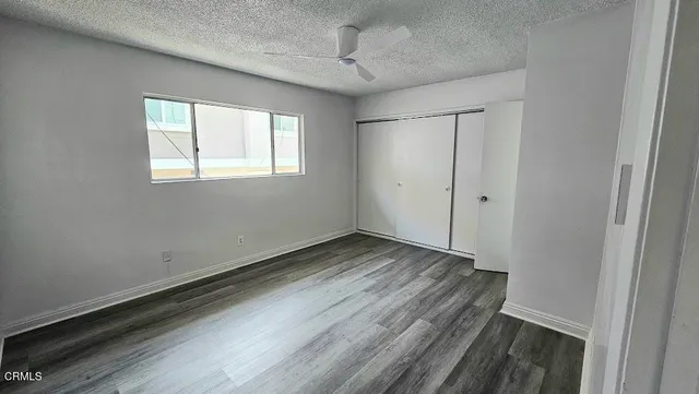 a view of an empty room with wooden floor and closet