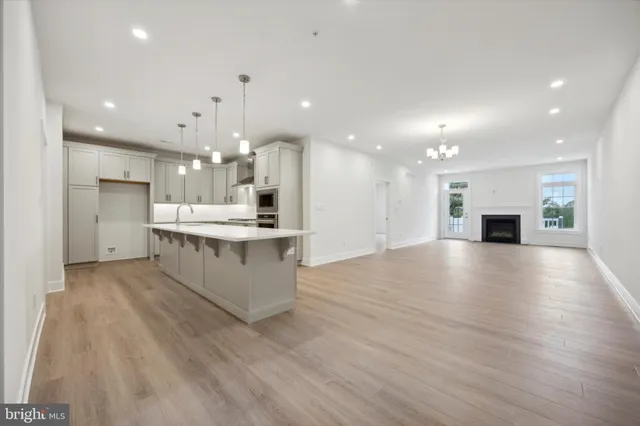 a large kitchen with a large counter top stainless steel appliances and wooden floor