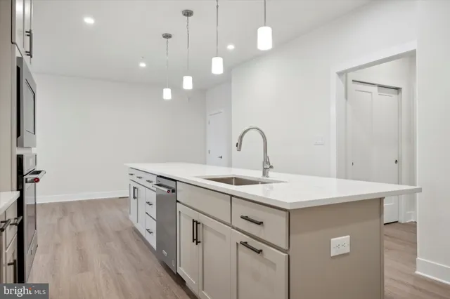a kitchen with a sink a counter space and wooden floor