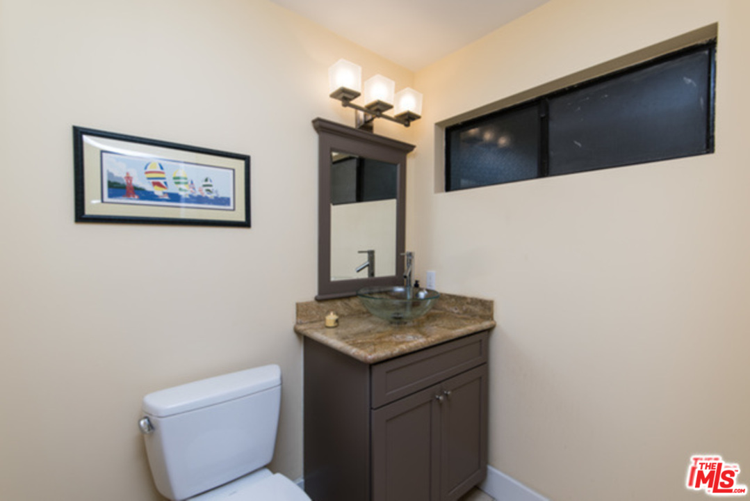 26664 Seagull Way, Unit A105 Malibu, CA 90265 - Photo 12 of 23 a bathroom with a granite countertop sink a toilet and mirror