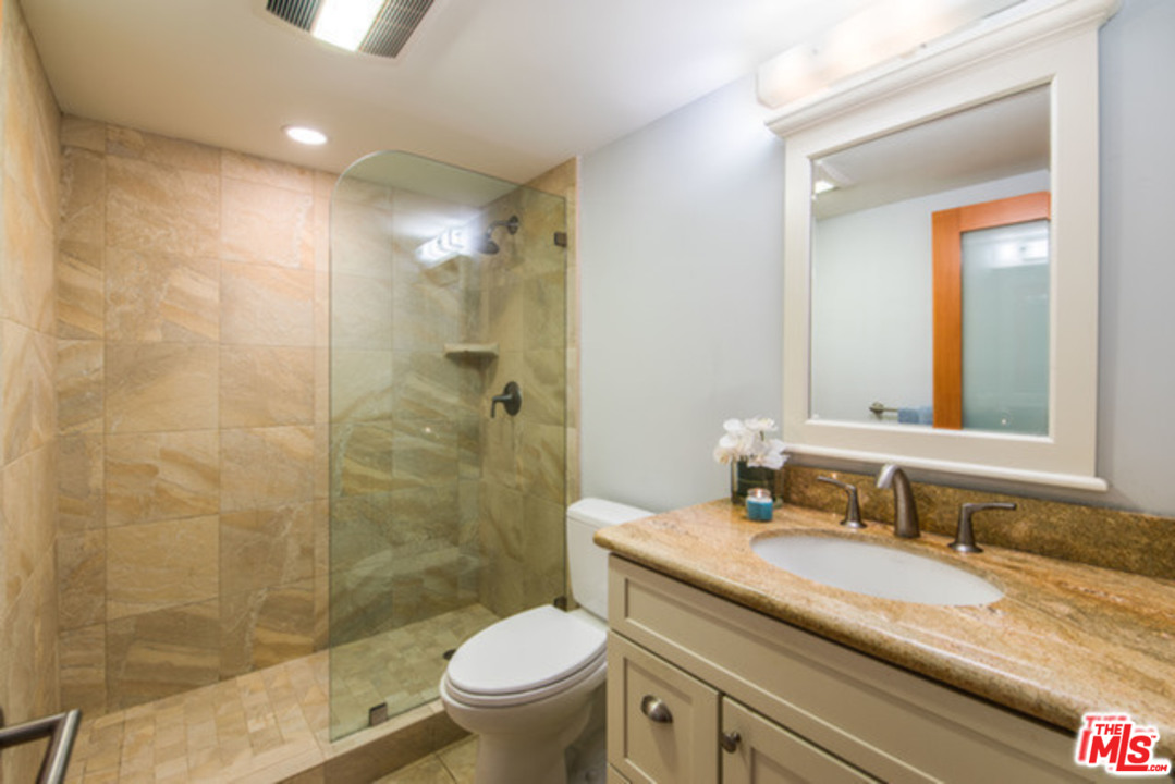 26664 Seagull Way, Unit A105 Malibu, CA 90265 - Photo 16 of 23 a bathroom with a granite countertop sink toilet mirror and shower