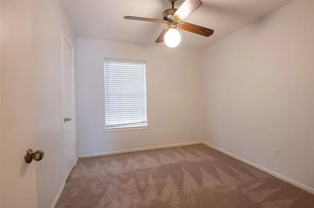 an empty room with a window and a fan
