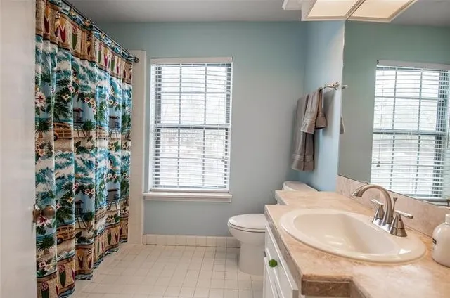a bathroom with a sink a toilet and a window