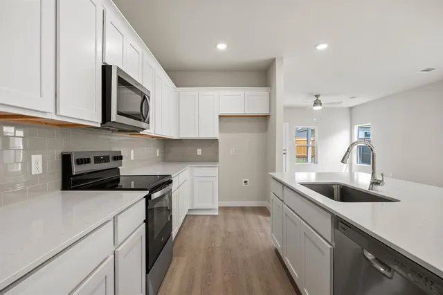 a kitchen with stainless steel appliances granite countertop a sink and dishwasher a stove top oven with wooden floor
