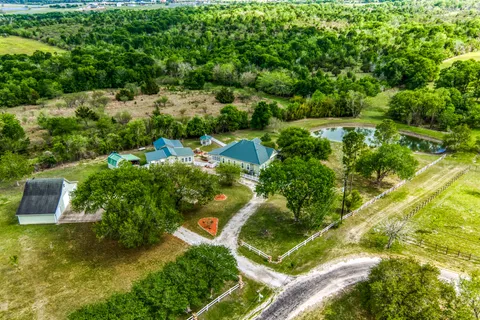an aerial view of residential house with outdoor space and trees all around