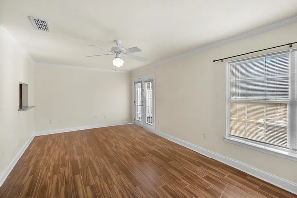 a view of an empty room with wooden floor and a window