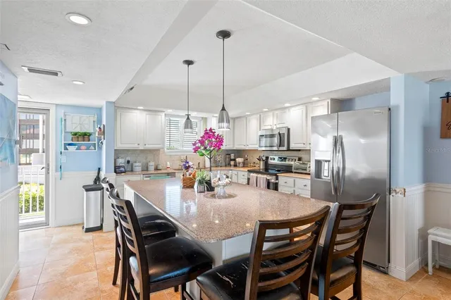 a dining room with stainless steel appliances kitchen island granite countertop a dining table chairs and granite counter tops