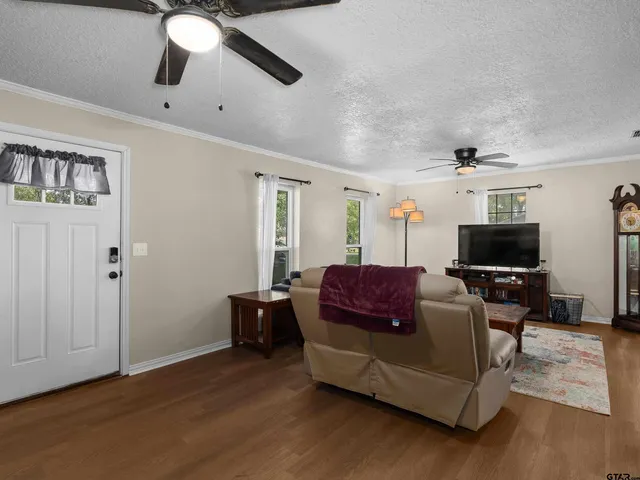 a living room with furniture a flat screen tv and kitchen view